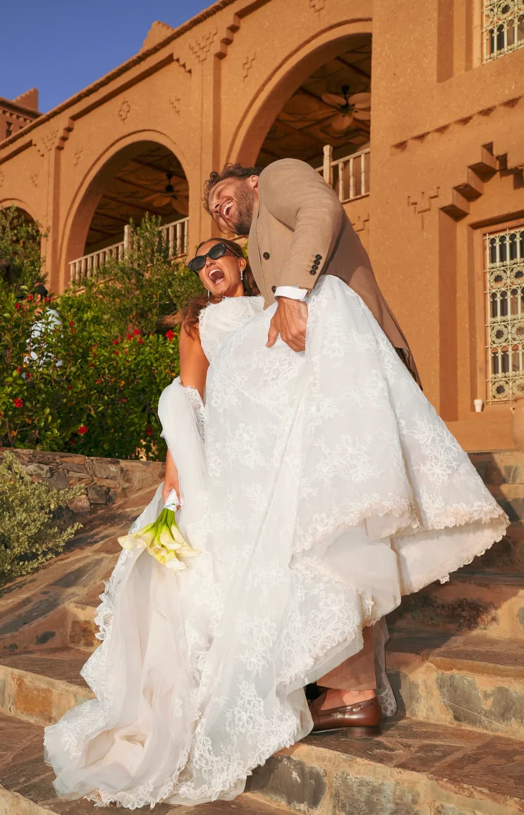 Groom lifting his bride on the kasbah steps at golden hour near Marrakech
