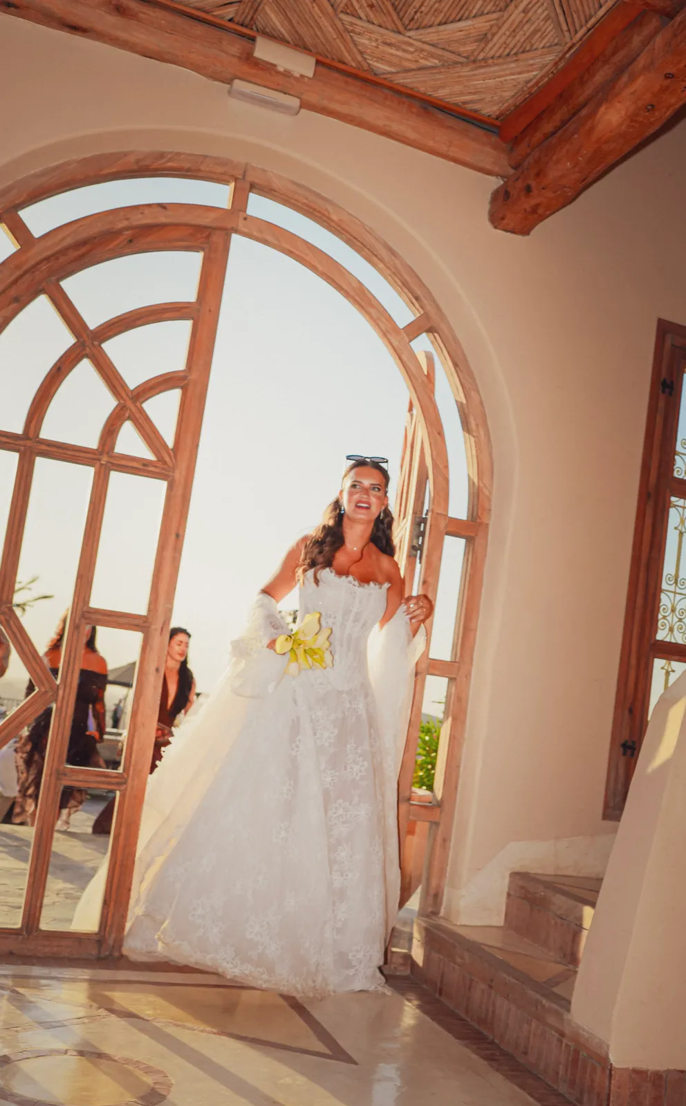 Bride stepping through an arched wooden door into the Agafay kasbah venue