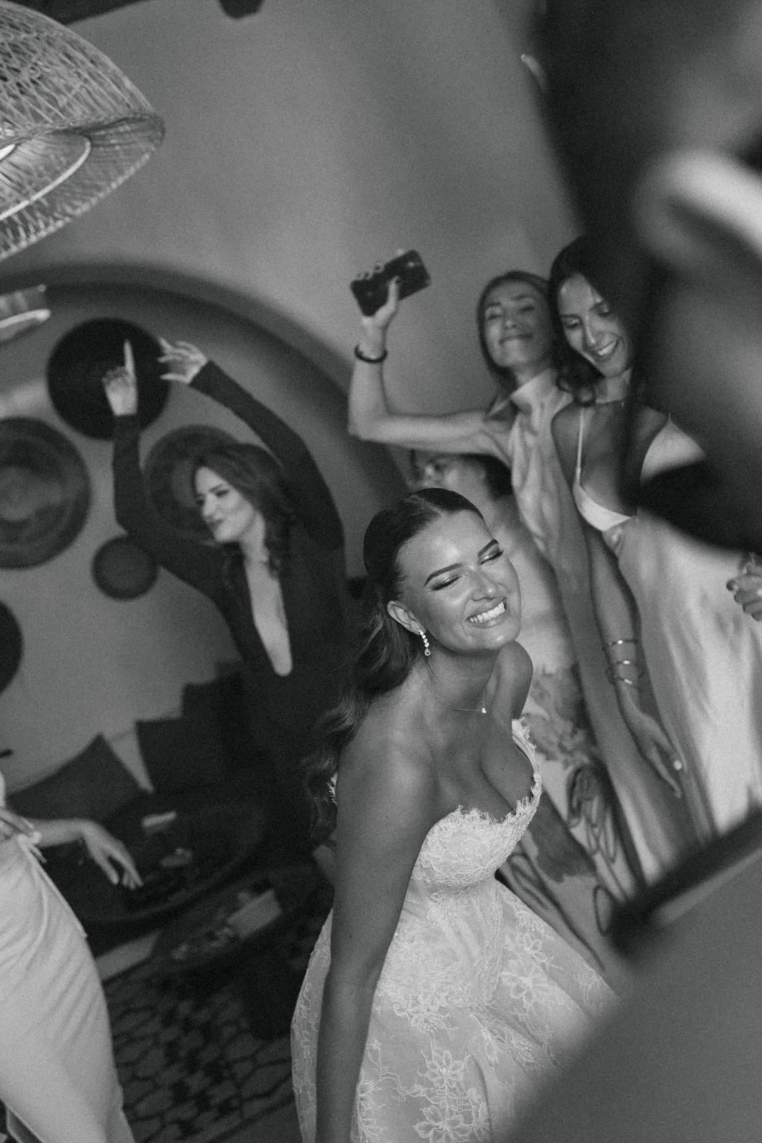 Bride celebrating on the dance floor surrounded by friends, black and white