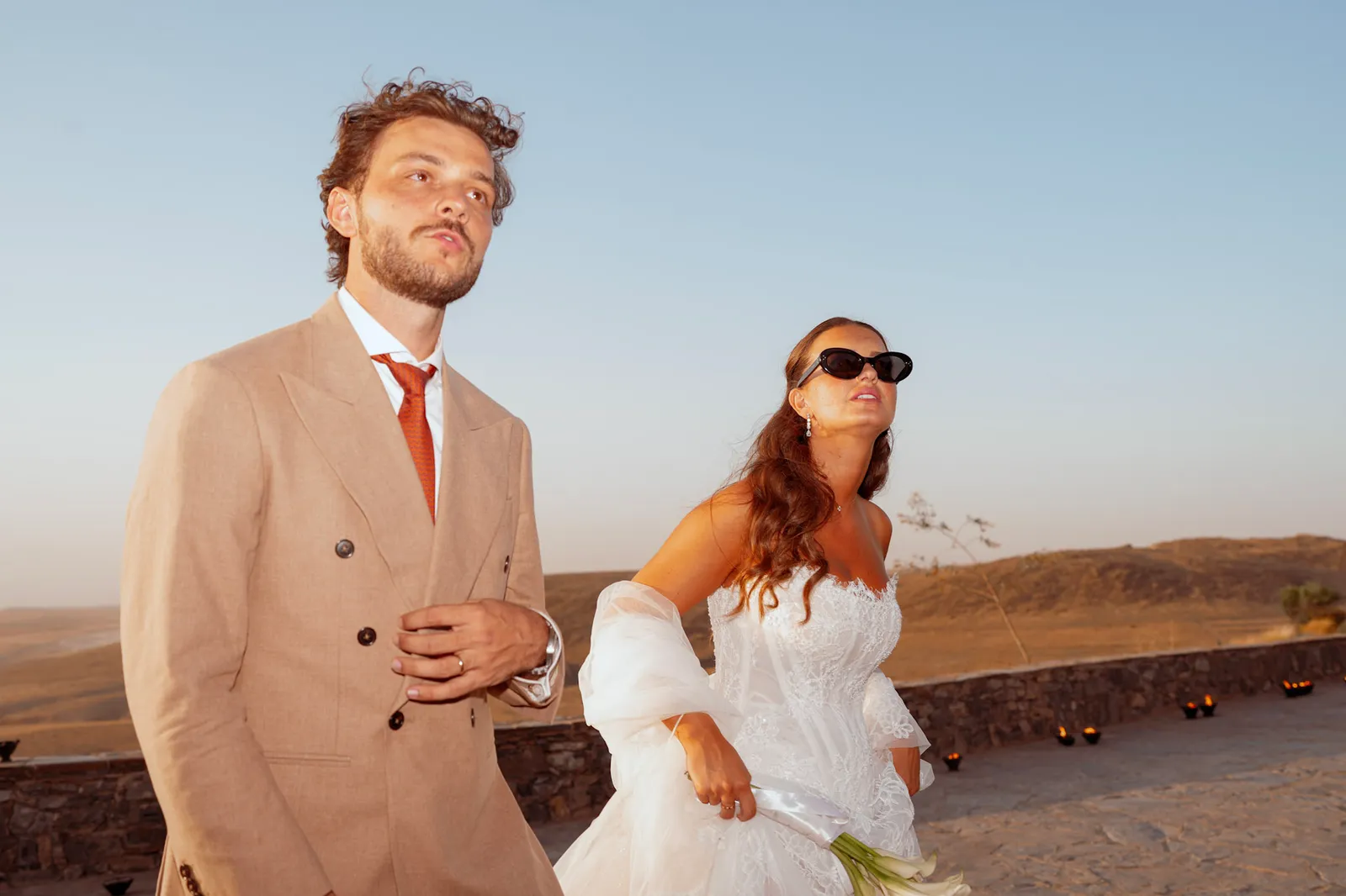 Couple walking a candlelit desert terrace at dusk, Agafay wedding near Marrakech