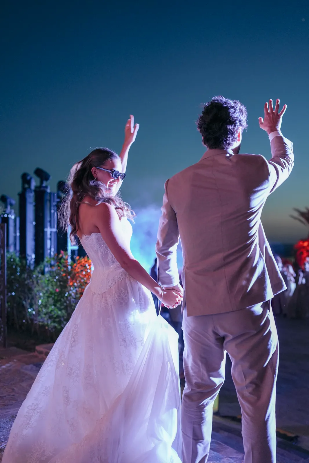 Bride and groom dancing under stage lights at their desert evening party