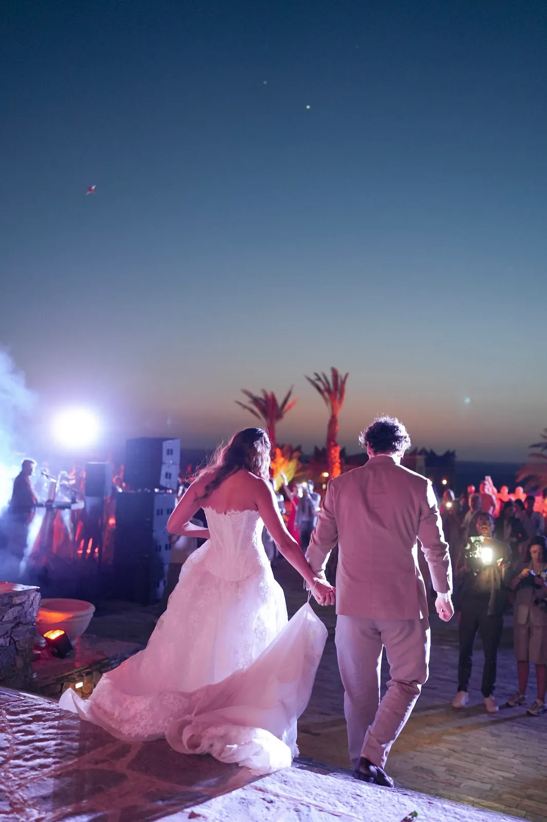 Couple walking hand in hand toward the stage as the desert party begins