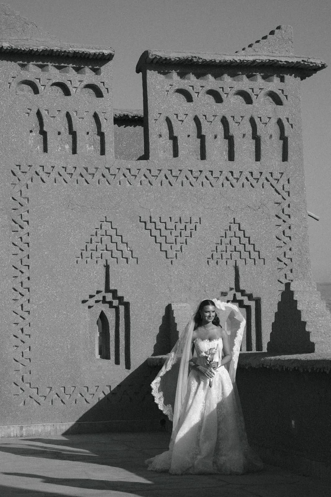 Bride and groom beneath the veil on a kasbah rooftop, black and white