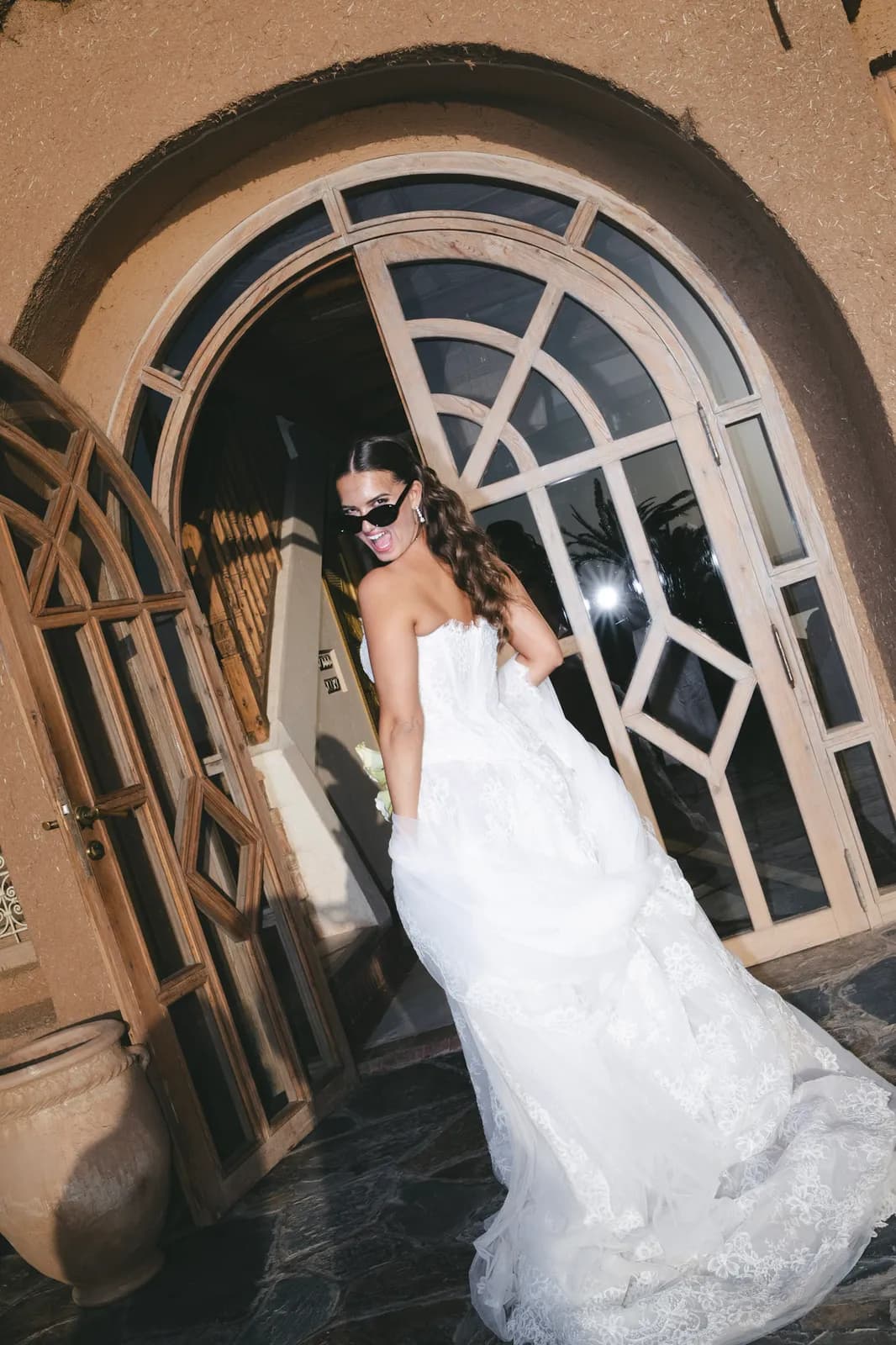 Bride entering the lamplit kasbah doors in the evening, lace train trailing